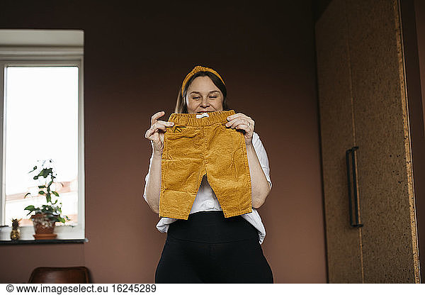 Woman in bedroom holding baby trousers