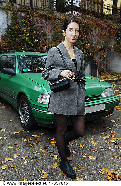 Woman in business suit near green car