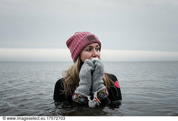 woman in cold water in the ocean with hat and gloves on