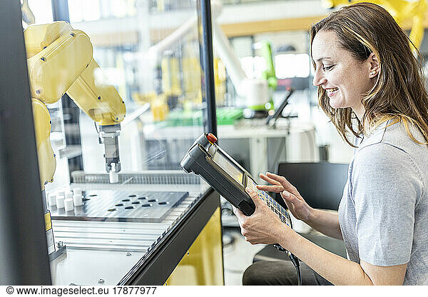 Woman in factory using control of industrial robot