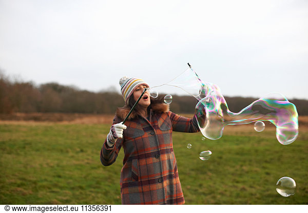 Woman in field using bubble wands to make bubbles