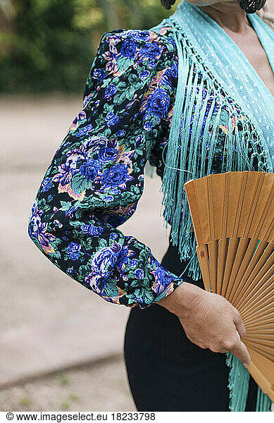 Woman in flamenco costume holding folding fan