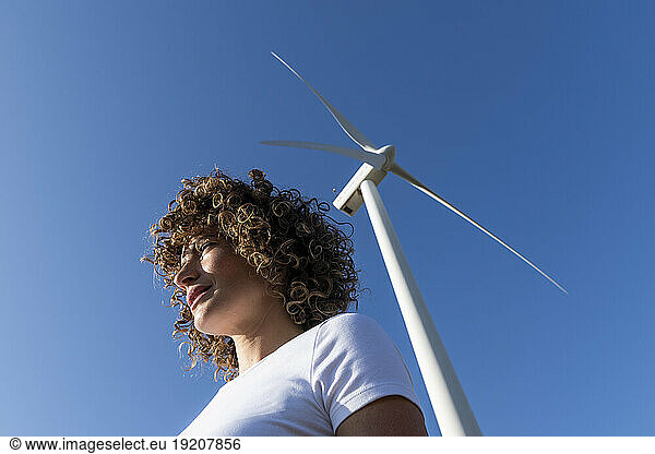 Woman in front of wind turbine on sunny day