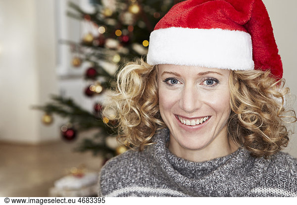 Woman in front of xmas tree wearing hat