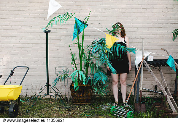 Woman in garden camouflaged by pot plant