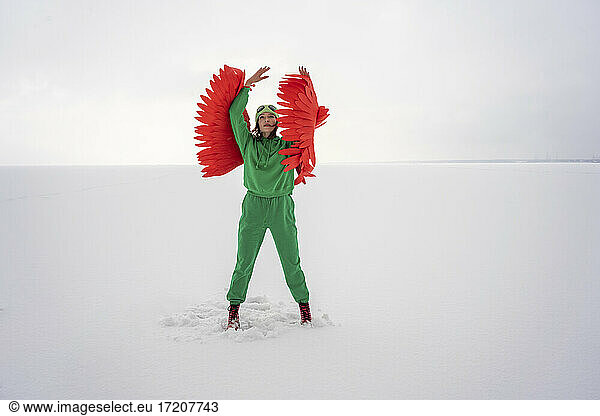 Woman in green bird costume looking up while standing against sky