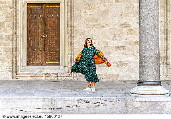Woman in green dress and orange scarf exploring Istanbul on vacation
