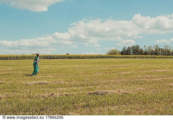 Woman in green walks through summer sunny field