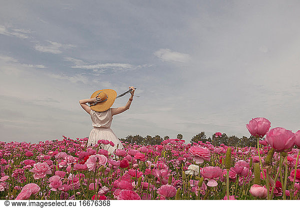 Woman in hat in field of pink flowers