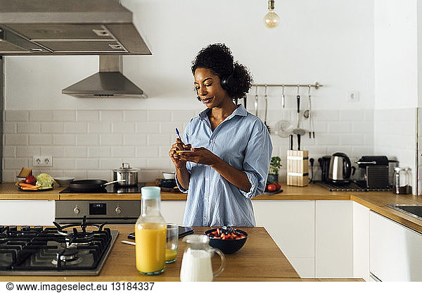 Woman in her kitchen in the morning  writing notes