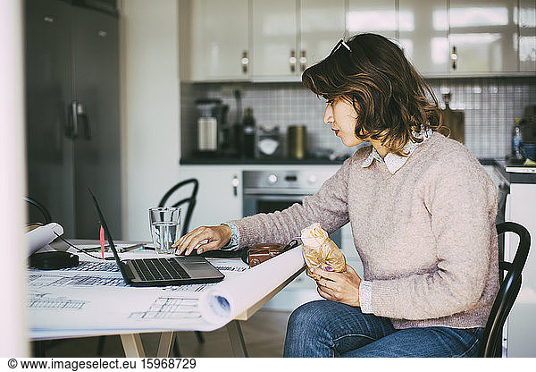 Woman in kitchen working from home having lunch