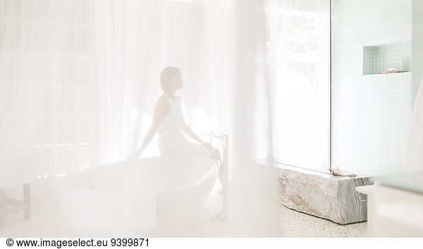 Woman in modern bathroom viewed through sheer curtain
