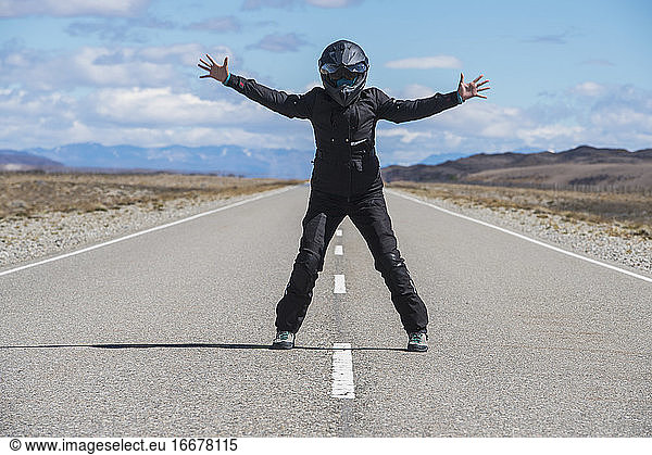 woman in motorbike gear standing in the middle of empty highway