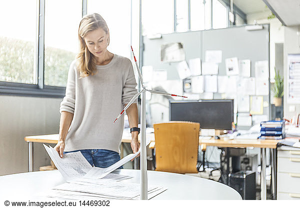 Woman in office working on plan with wind turbine model on table