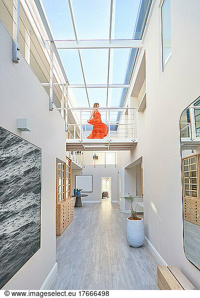 Woman in orange dress walking across catwalk in modern home