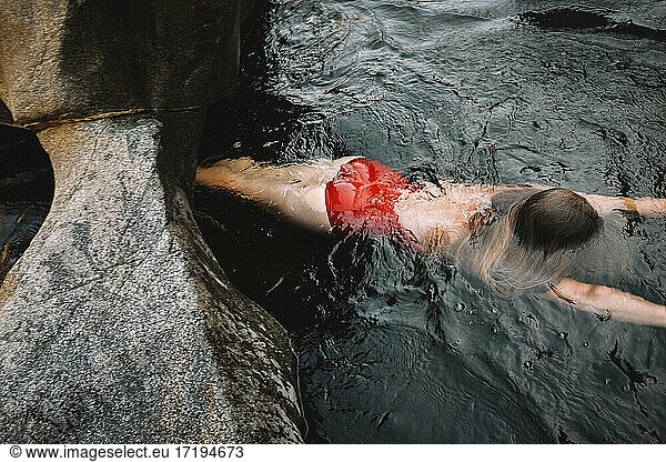 Woman in Red Bathing Suit Floats in Black Water
