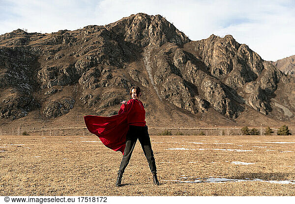 Woman in red coat dancing next to the mountain