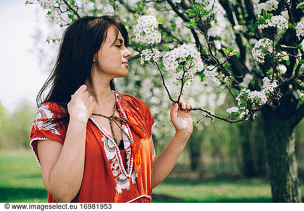 Woman in red dress smelling white flowers
