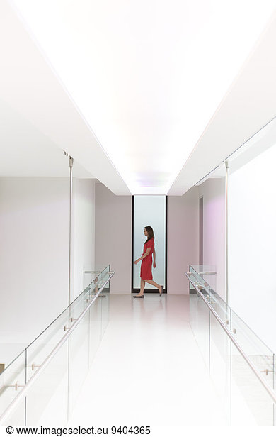 Woman in red dress walking through white modern corridor