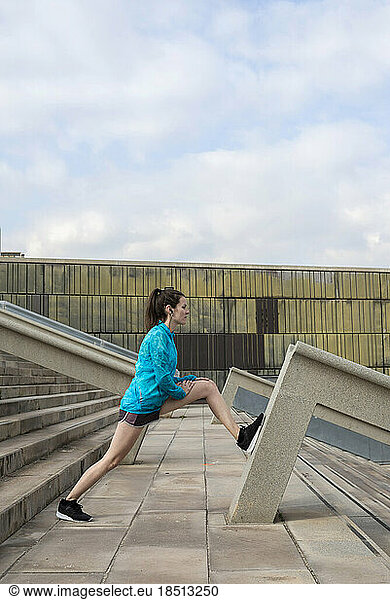 Woman in sportswear doing stretch in urban setting