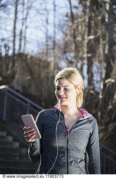 Woman in sportswear listening music on smart phone