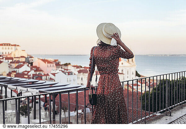 Woman in straw hat and dress on a view point in Lisbon  Alfama