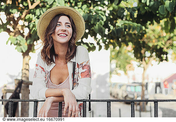 Woman in straw hat on the streets of Lisbon  smiling and looking aside