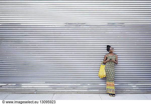 Woman in sunglasses standing against shutter