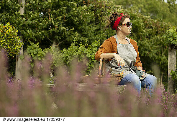 Woman in sunglasses taking a break from gardening in summer backyard