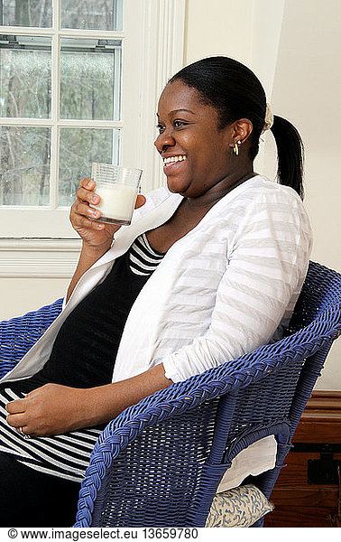 Woman in the third trimester of pregnancy drinks a glass of milk. Milk is a source of important nutrients  including calcium  protein and Vitamin D.