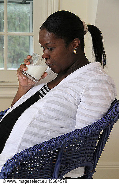 Woman in the third trimester of pregnancy drinks a glass of milk. Milk is a source of important nutrients  including calcium  protein and Vitamin D.
