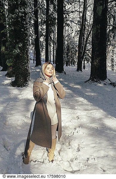 Woman in warm clothing spending leisure time at winter forest