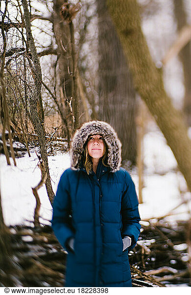 Woman in warm fur lined hood coat in snow forest