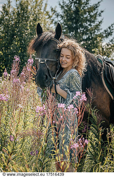Woman in wildflowers talking to a horse.
