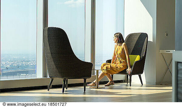 Woman in yellow suit looking outside of the giant window in New York