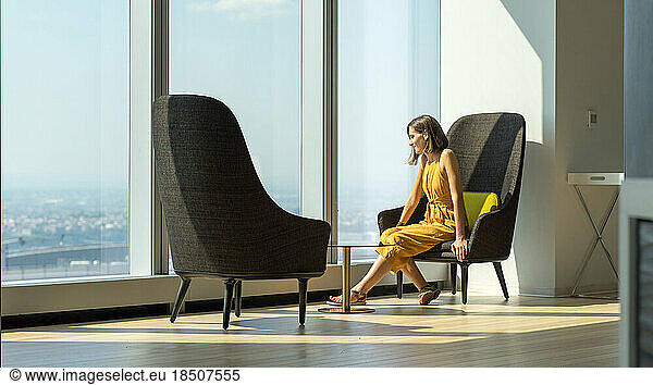 Woman in yellow suit looking outside of the giant window in New York