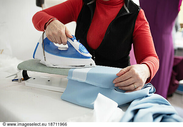 woman ironing a blue cloth