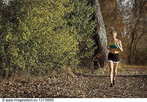 Woman jogging on field by forest