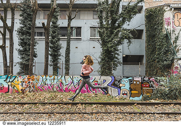 Woman jumping in the air between abandoned railway tracks