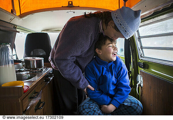 Woman kisses her son on head in VW camper van during family road trip