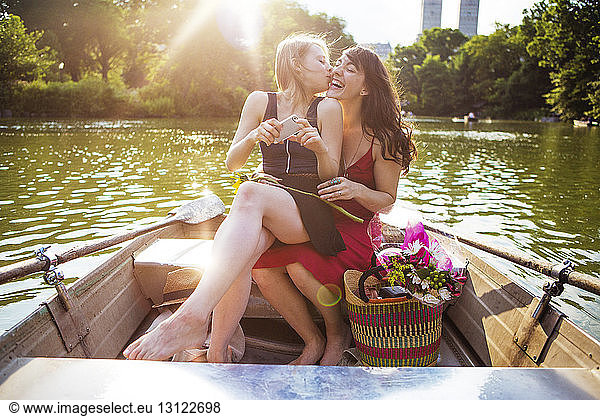 Woman kissing girlfriend while traveling in boat on lake