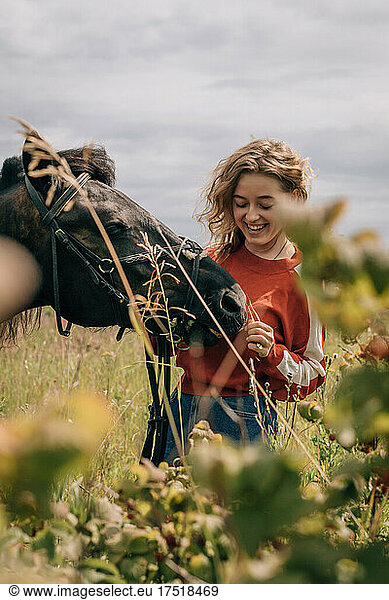 Woman laughing at horse in field  lifestyle.