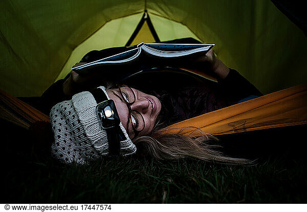 woman laying in a tent reading whilst camping alone