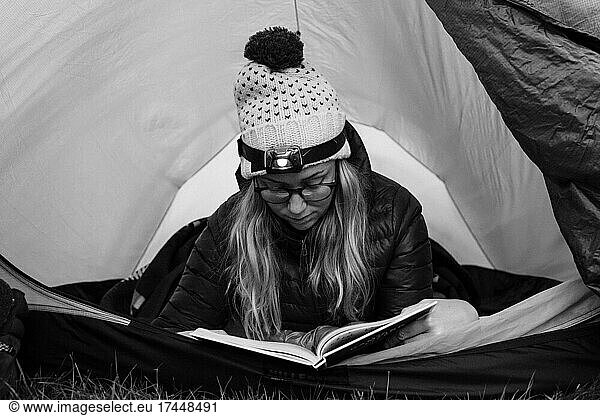 woman laying in her tent reading whilst camping alone