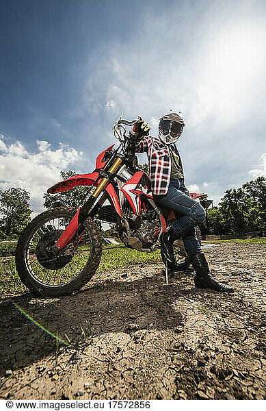 woman leaning on her dirt bike on race track