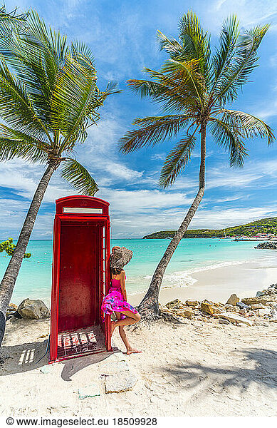 Woman leaning on palm tree beside phone box  Dickenson Bay  Antigua