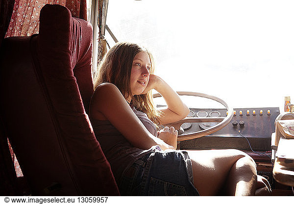 Woman leaning on steering wheel while sitting in camper van