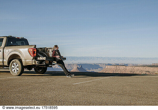 Woman leans against tailgate of pickup truck looking at view  Utah