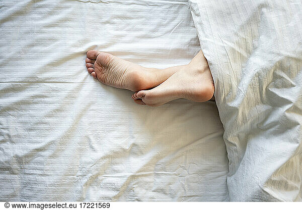 Woman legs crossed at ankle on bed