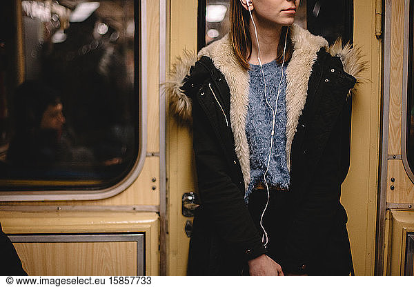 Woman listening music on earphones while traveling in subway train